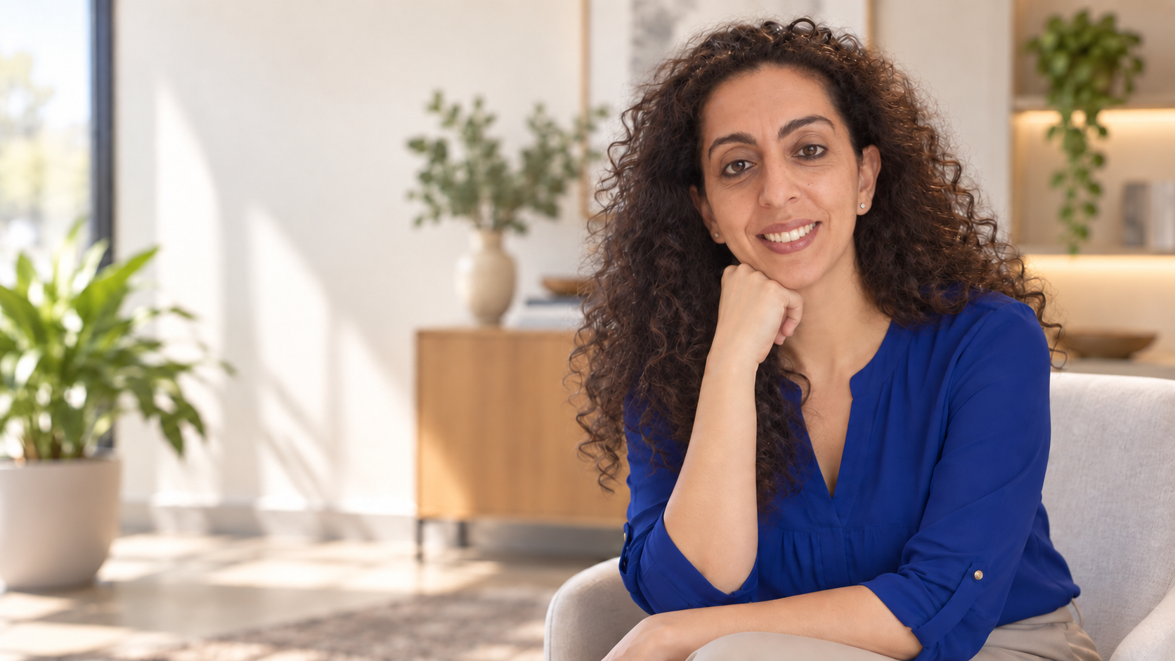 Sherry Sayari seated in a bright professional setting wearing a blue blouse